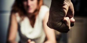 Image of a fist in the foreground and a woman sitting in the background