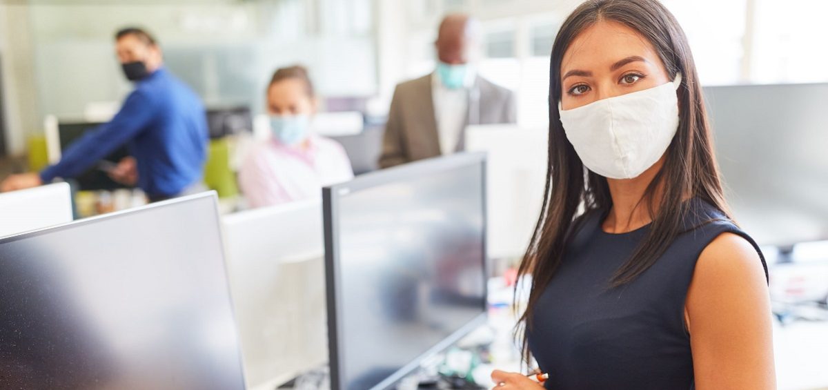 Young businesswoman with face mask as protection