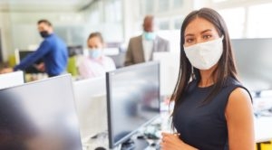 Young businesswoman with face mask as protection