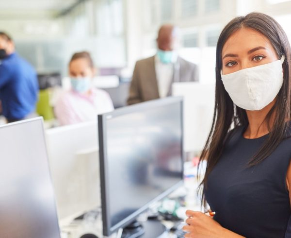 Young businesswoman with face mask as protection