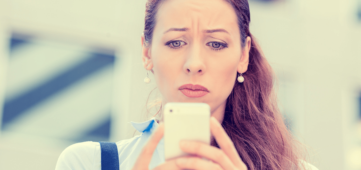 An image of a concerned woman looking at her phone.